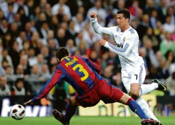 Barcelonan Gerard Pique myöhästyy tilanteesta ja Real Madridin Cristiano Ronaldo lentää nurmen pintaan.