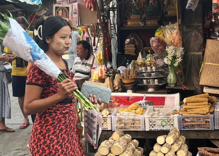 Myanmarilainen nainen kävelee Mae Sotin torin halki. Torilla myydään kaarnaa, jota jauhetaan Myanmarissa suositun kosmeettisen voiteen raaka-aineeksi.