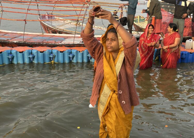 Pyhiinvaeltaja rukoilee jokien yhtymäkohdassa Maha Kumbh Sangamilla. Kaksi jokea, Ganges ja Yamuna, ovat näkyviä. Myyttisen Saraswatin sanotaan olevan piilossa maan alla.